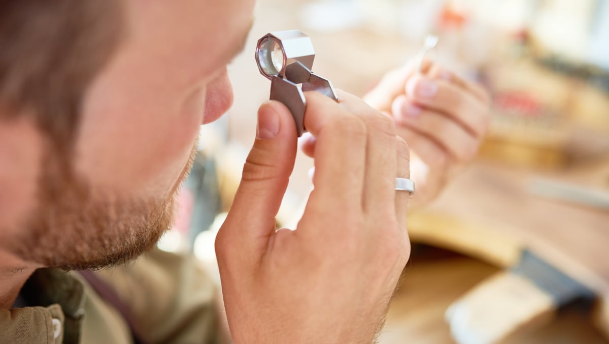 Préteur sur gage Homme examinant un bijou à la loupe