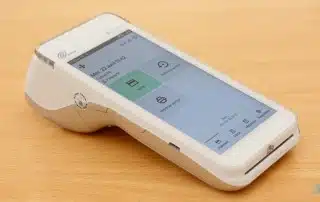 Terminal de Flatpay vue 3/4 gauche sur une table en bois